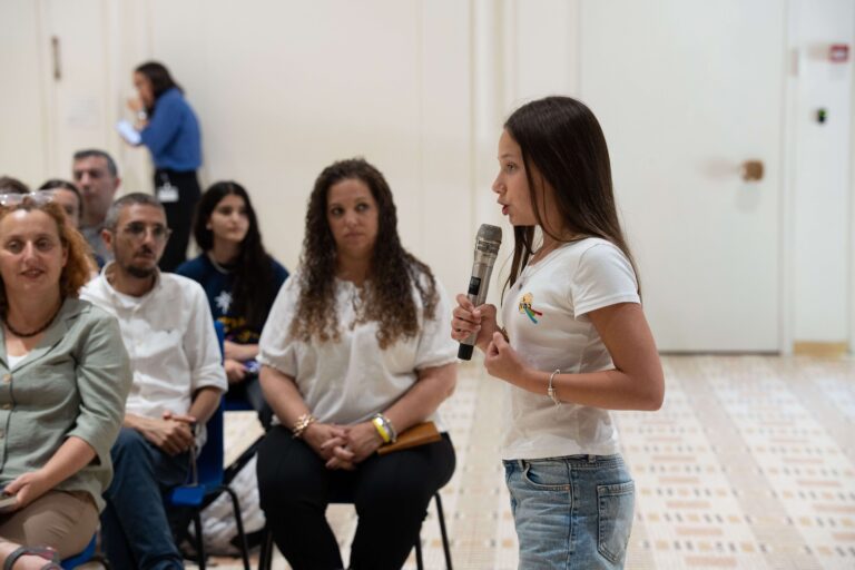 נערה נואמת מול קהל במסגרת פרויקט להיות יעודי