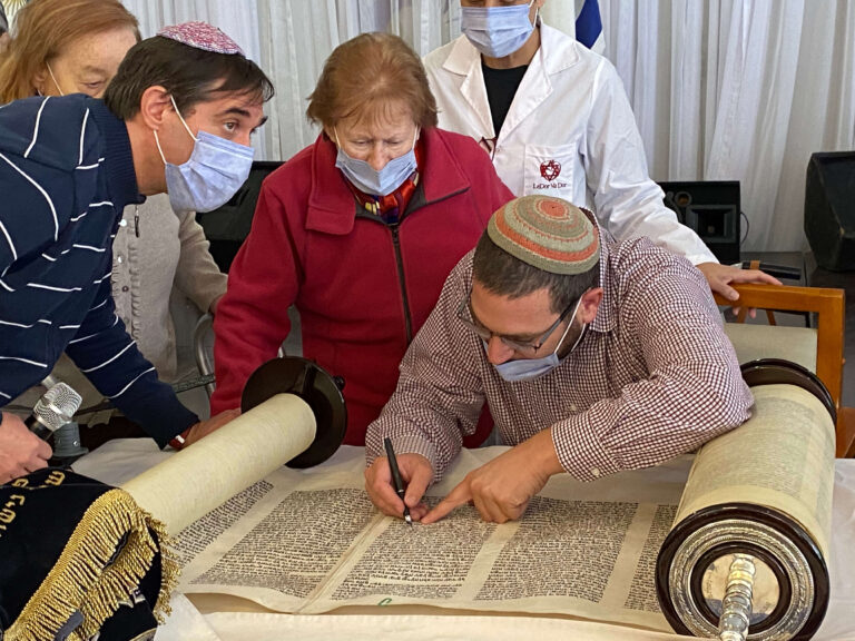 4 אנשים כותבים אותיות בספר תורה