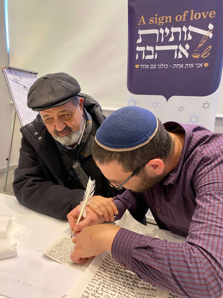 2 אנשים כותבים אותיות בספר תורה