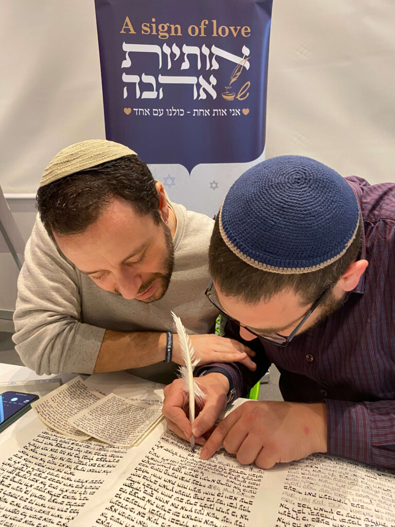 2 אנשים כותבים אותיות בספר תורה